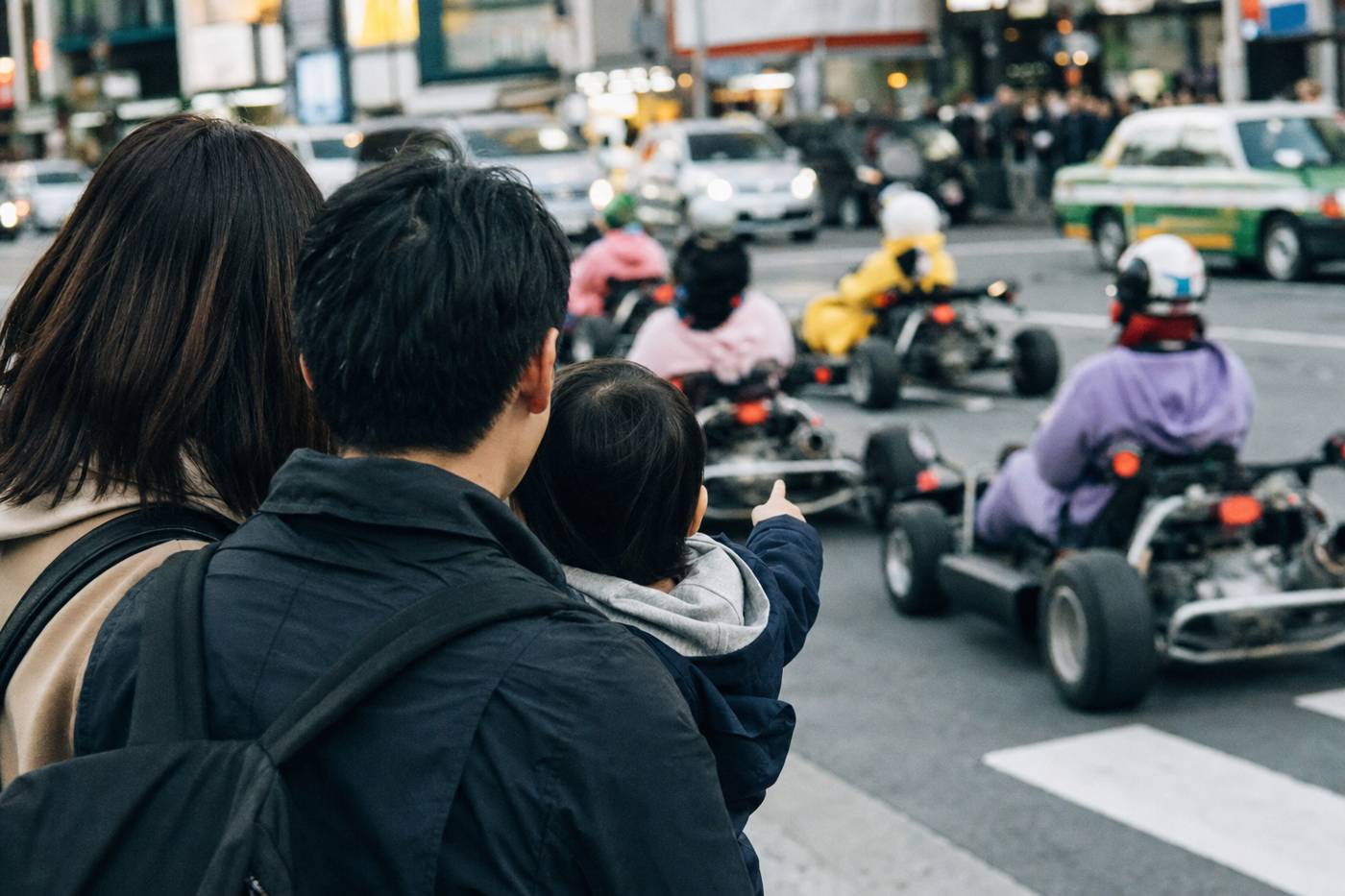 Eine Familie beobachtet einen vorbeifahrenden Kart-Konvoi in Shibuya