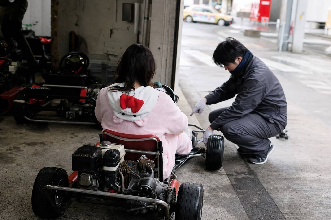 Einem Erstfahrer werden in einer Tokioter Garage die Bedienelemente des Karts gezeigt