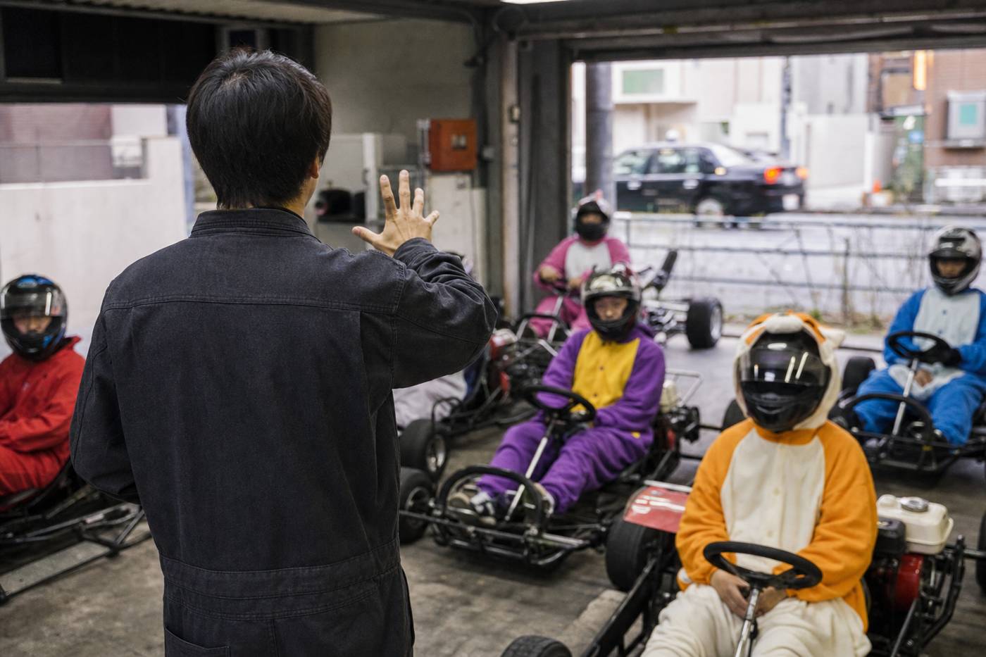 Personal weist sitzende Kart-Fahrer in einer Tokioter Garage ein