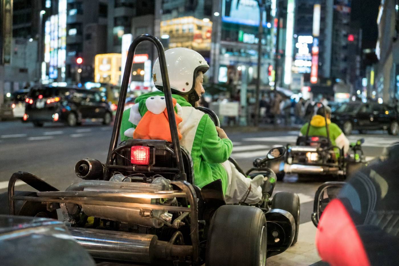 Fahrer mit Helm genießt eine Street-Kart-Fahrt durch das neonbeleuchtete Shibuya