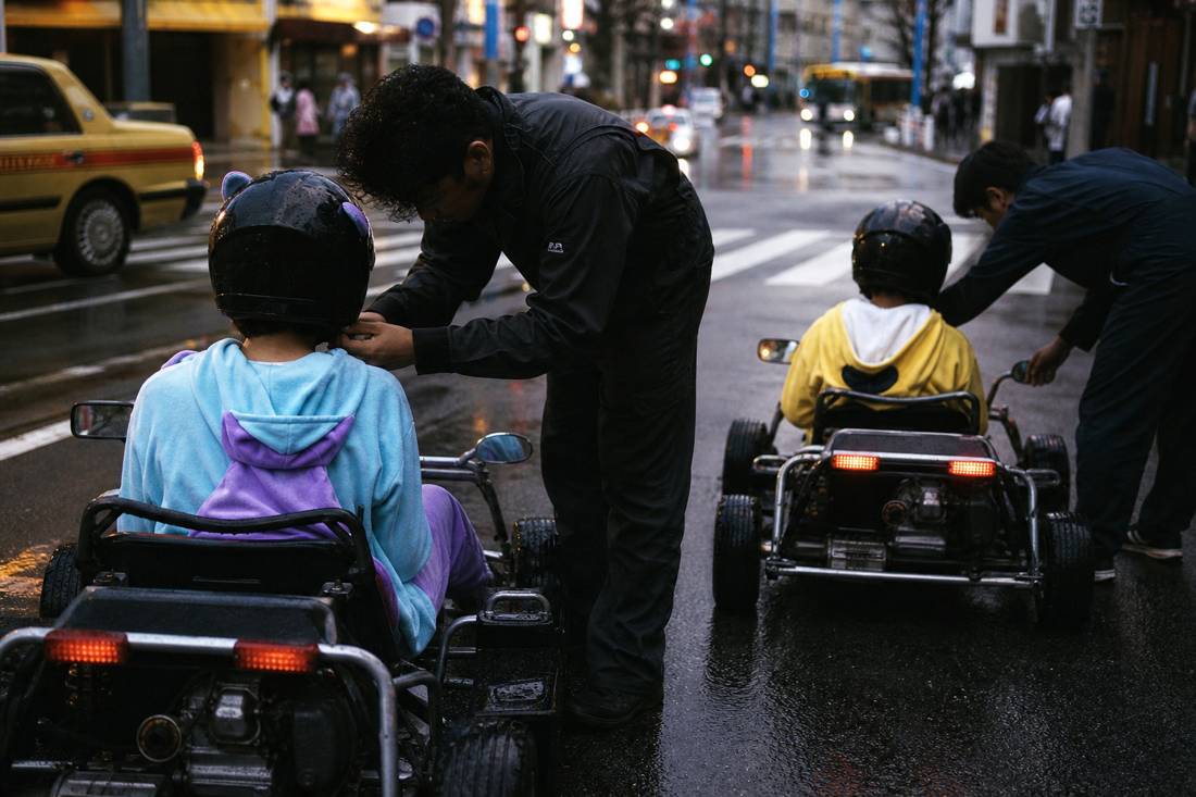 Le personnel installant les conducteurs dans les karts dans un garage de Tokyo