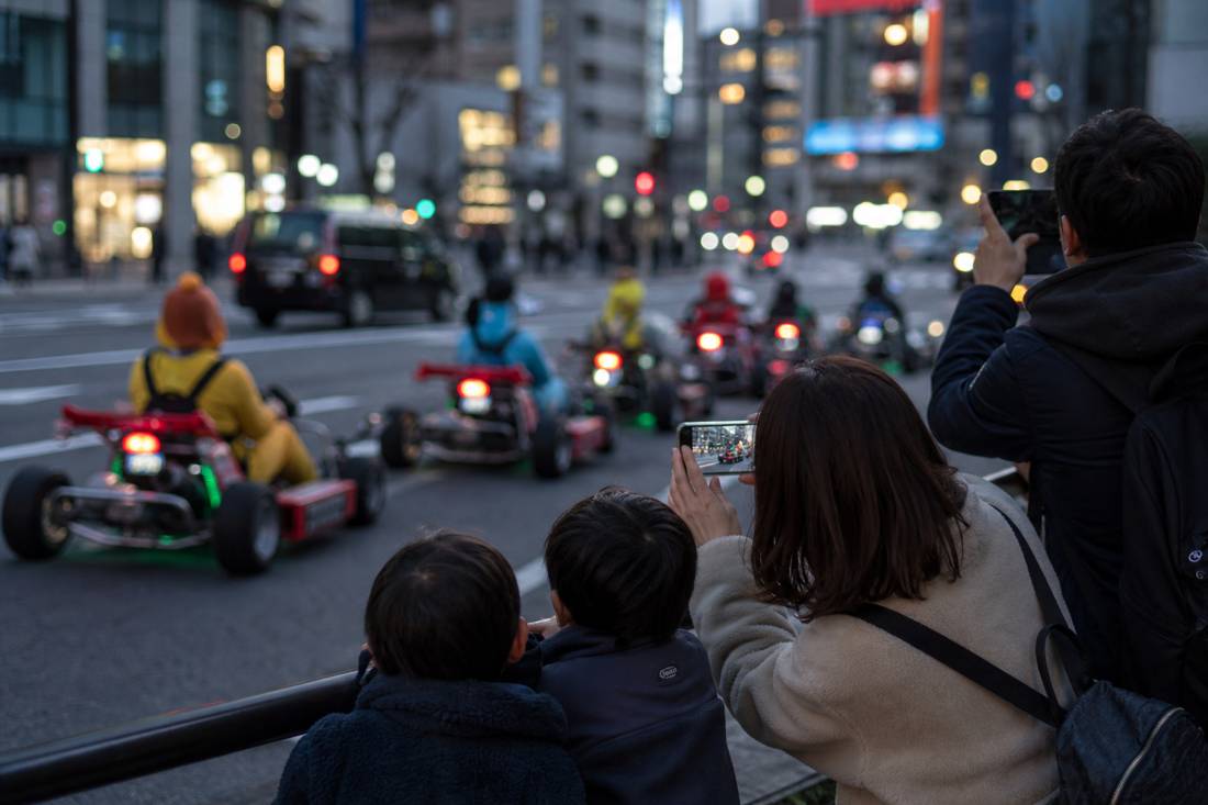 Une famille photographiant des karts dans une rue en néon de Tokyo