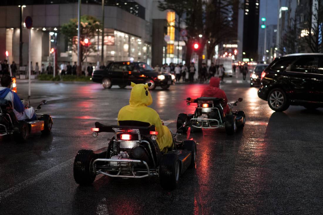 Karts in einer regnerischen Nacht in Tokio mit Neonspiegelungen