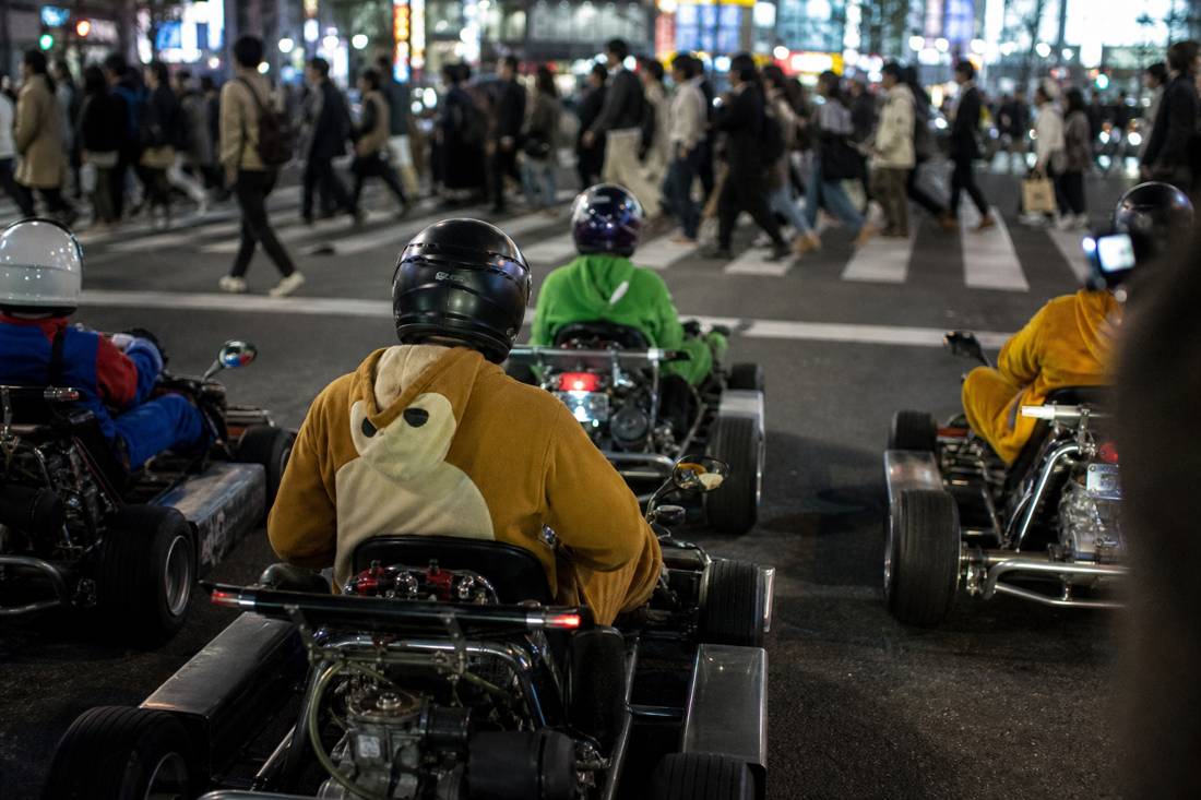 Go-kart in attesa al semaforo rosso mentre i pedoni attraversano l'incrocio di Shibuya