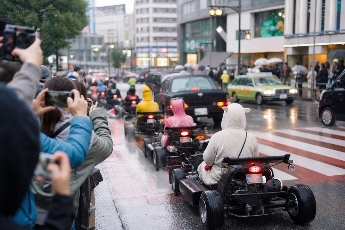 Pedoni che fotografano un convoglio di go-kart all'incrocio di Shibuya