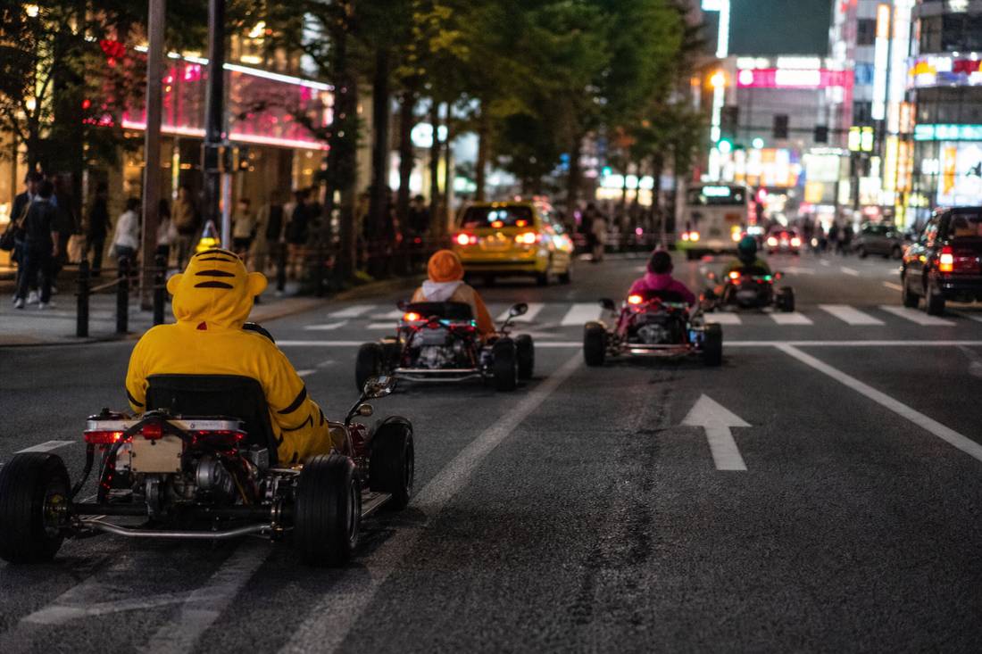 間隔を保ちながら東京の大通りを先導するガイドとゴーカートの車列