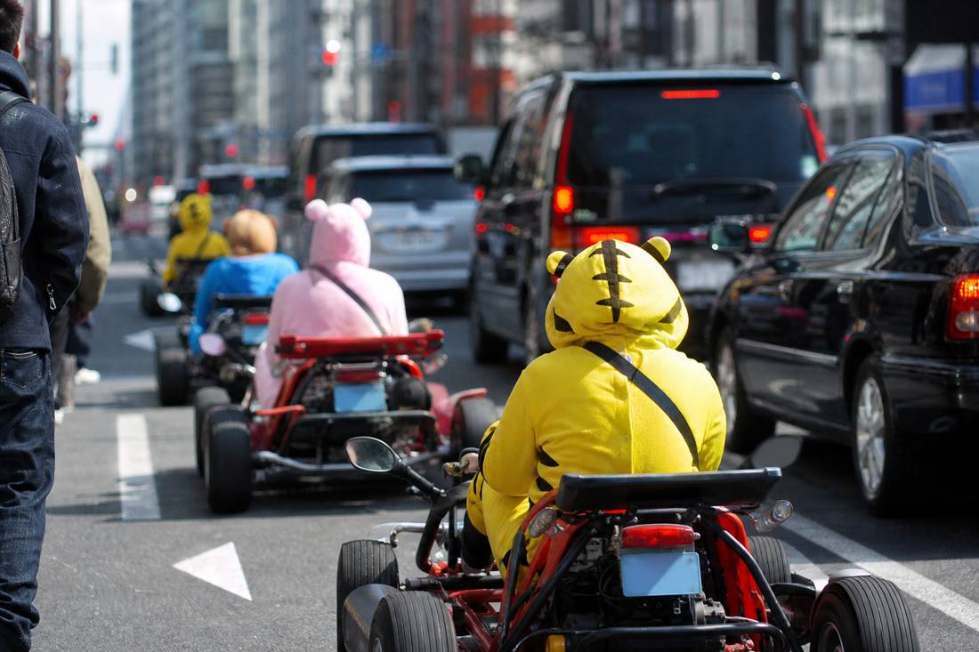 Des karts au niveau de la rue dans la circulation dense de Tokyo, à côté des taxis