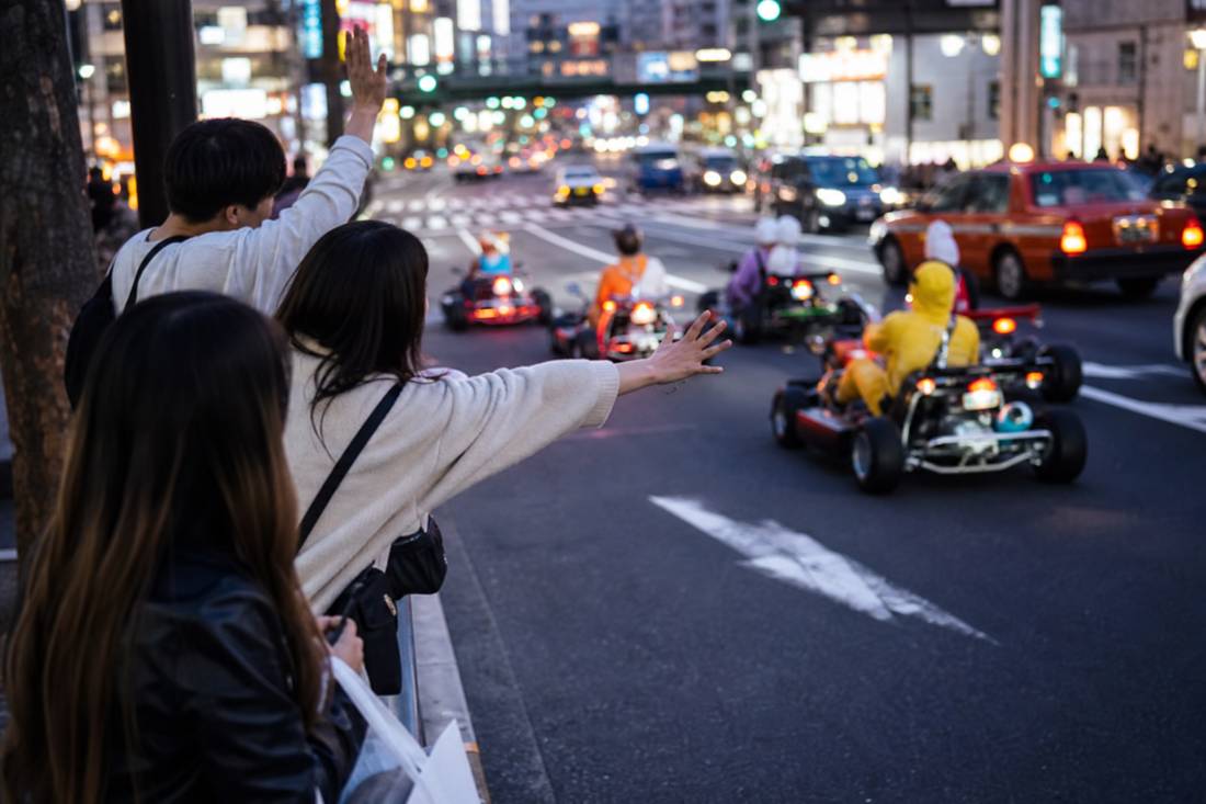 Des piétons saluant des karts qui passent à Shibuya