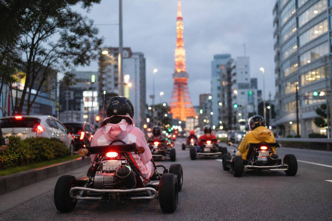 Des karts roulant le soir vers la Tokyo Tower illuminée