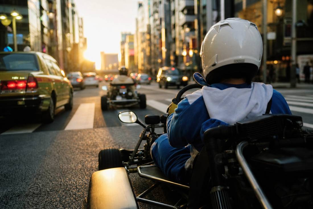 Guidatore con casco che guida un go-kart da strada attraverso Shinjuku