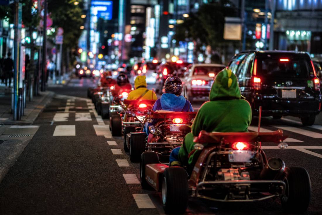 Le luci posteriori di un convoglio di kart di notte in un canyon di neon a Tokyo