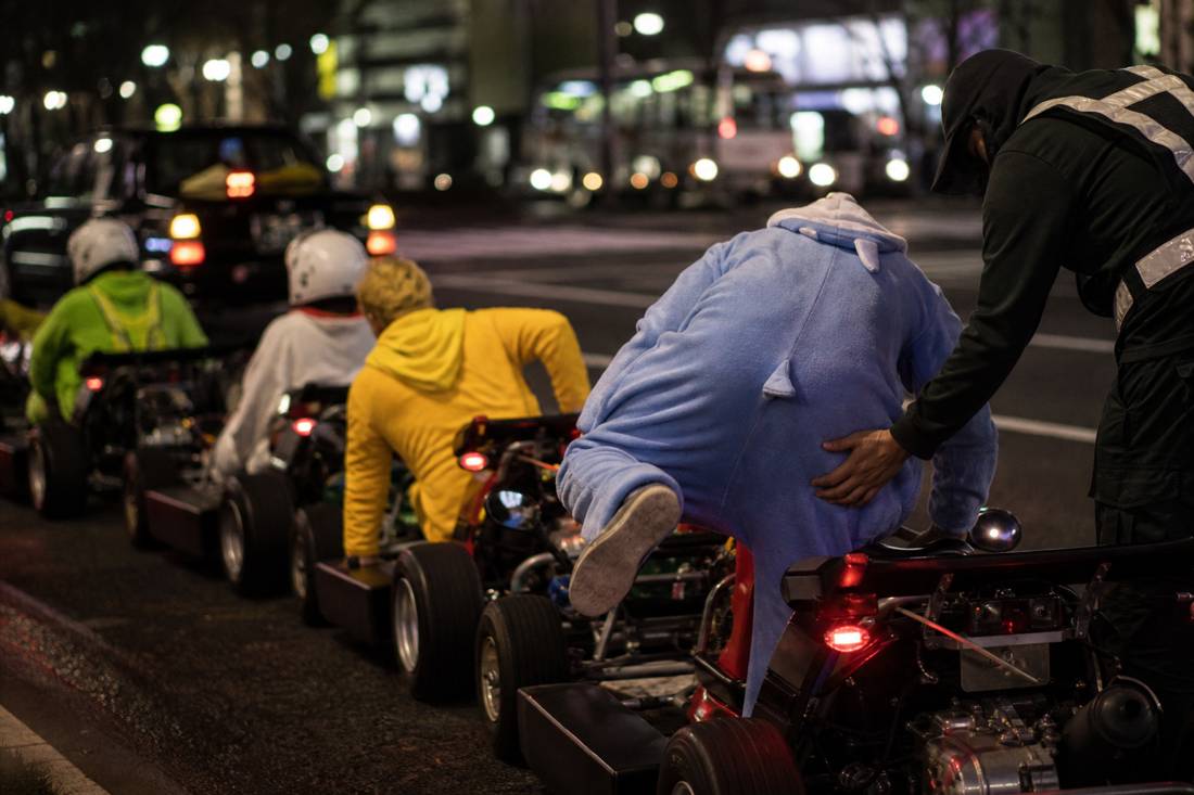 Fahrer steigen in einer Tokioter Garage in die niedrigen Kart-Sitze