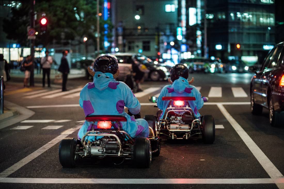 Una coppia anziana sui go-kart a un semaforo rosso di Tokyo