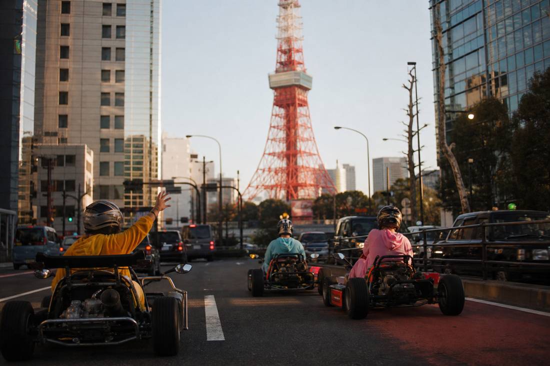 Go-kart che passano con calma davanti alla Tokyo Tower alla luce del giorno