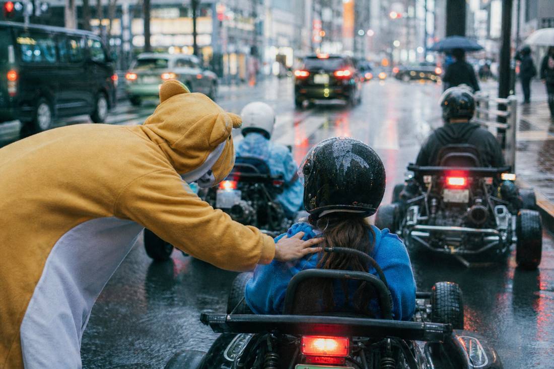 Una guida che controlla un guidatore di go-kart a una sosta a Tokyo