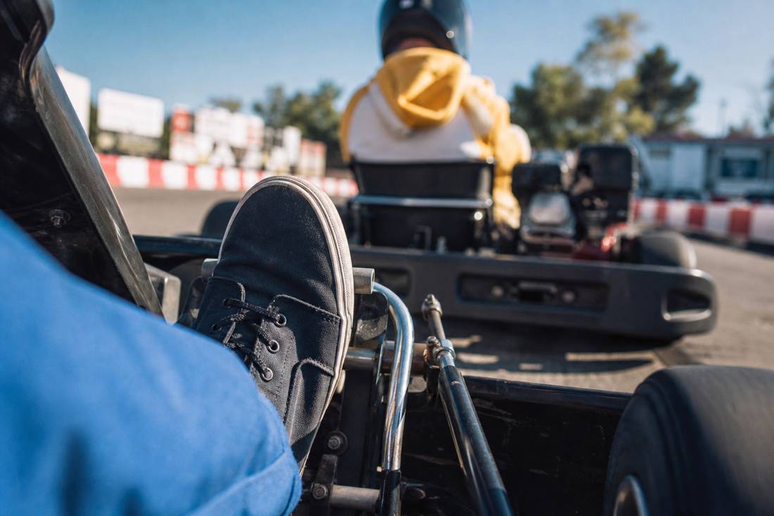 Geschlossene Sneaker auf den Pedalen eines Street-Karts