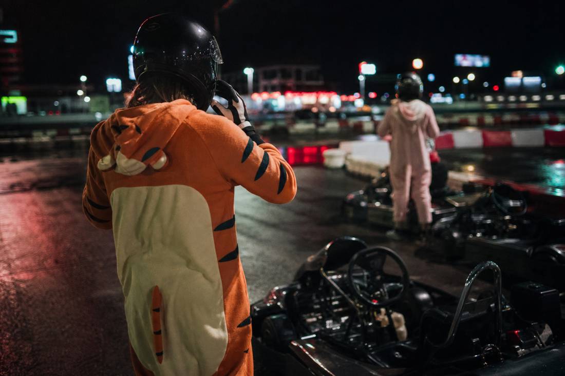 Ein Fahrer zieht neben einem Kart Handschuhe und Helm an