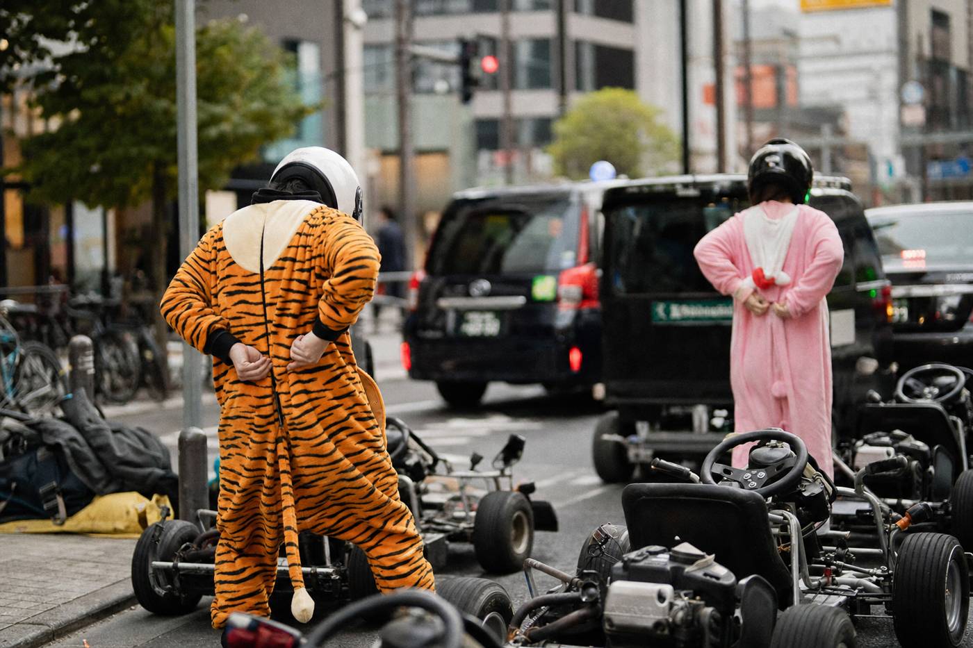 Fahrer ziehen neben Tokioter Karts bunte Ganzkörperkostüme über ihre Straßenkleidung